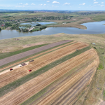 An aerial photo of brown and green land by a river or lake.