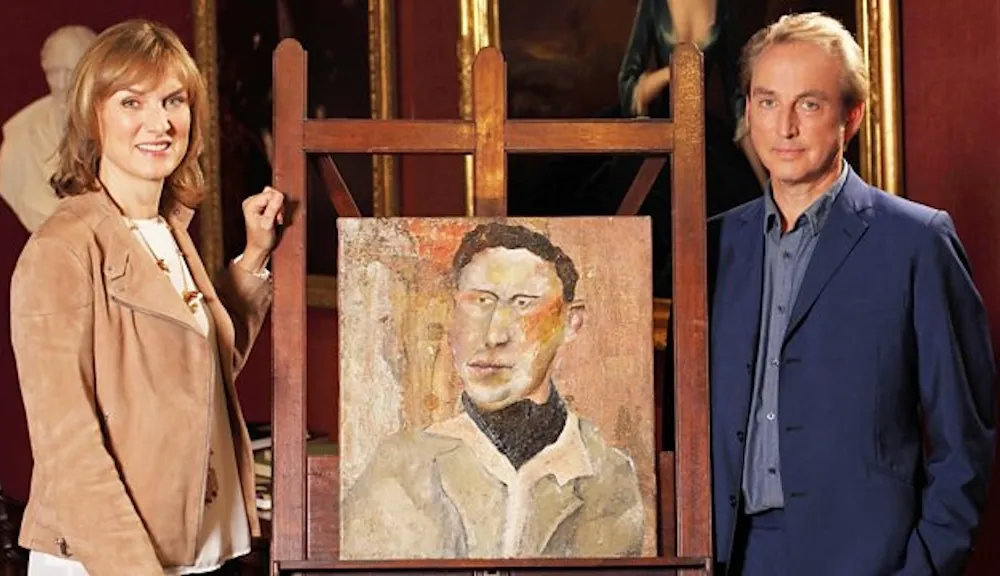 A man in a blue suit and a women in a leather jacket flank a smallish square painting of a man in a black scarf.