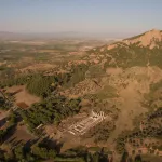 View of a rolling landscape with an archaeologic site in the center bottom.