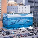 A photo shows a giant mural in Downtown Dallas depicting whales and dolphins swimming in the ocean.