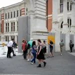 A crowd of masked visitors enters a museum.