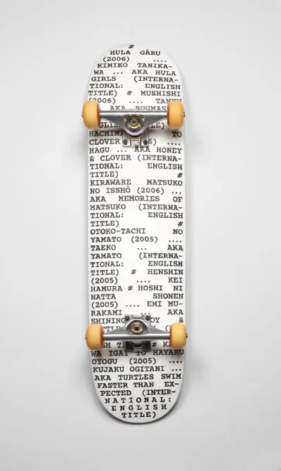 A photo shows the bottom of a skateboard, its white surface printed with black text