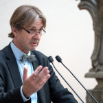 A man speaking at two microphones.