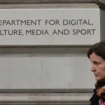 A woman walks by a sign that reads