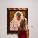 A woman staring at a painting of a woman in a white veil.