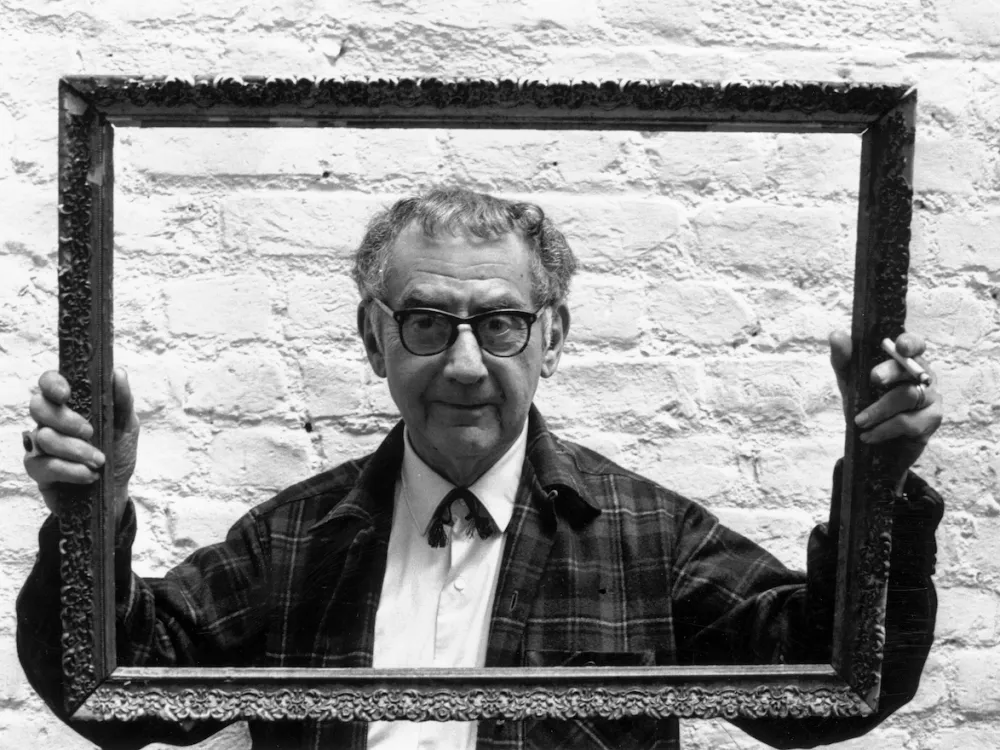 A photo portrait of a man holding an empty frame around his face.