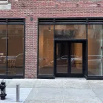 A brick building with glass doors and tall windows.