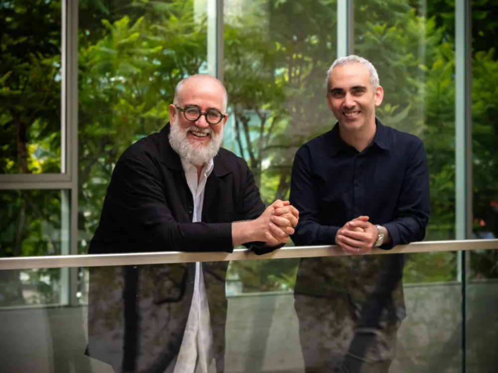 Photo of two men smiling on a balcony.