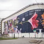 exterior view of a curved building with colorful images of flowers on the protruding wall