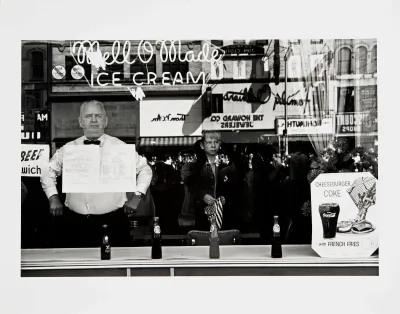 A photo shows a stout man and a young boy inside an ice cream shop whose window reflects the street outside