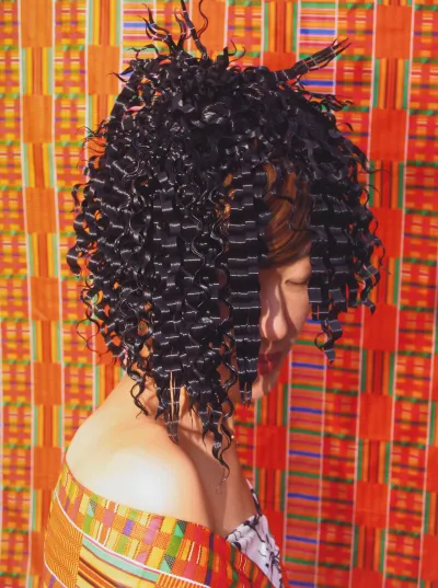 An artwork consists of a photograph of an Asian woman posing for the camera with a kinky black hairstyle. She stands in front of a seemingly African-style patterned background and wears a similarly patterned dress.