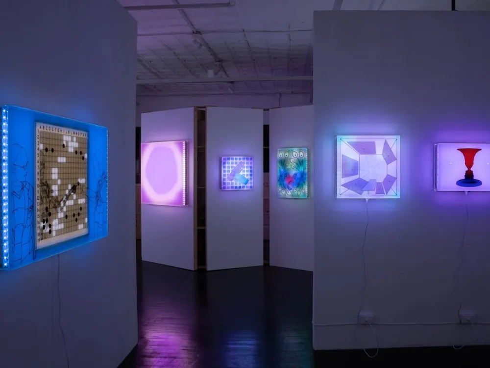 A gallery with backlit neon artworks hanging on its walls.