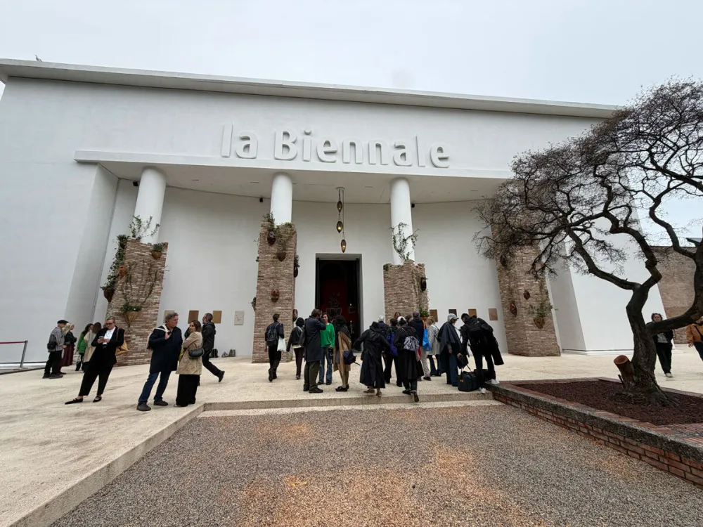 People stand in front of a white structure that reads