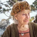 A smiling woman near the ocean.
