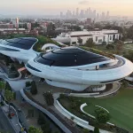 Aerial view of a space-like building with the downtown LA skyline in the background.