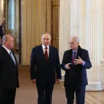Four older men in suits walking in an ornate museum gallery