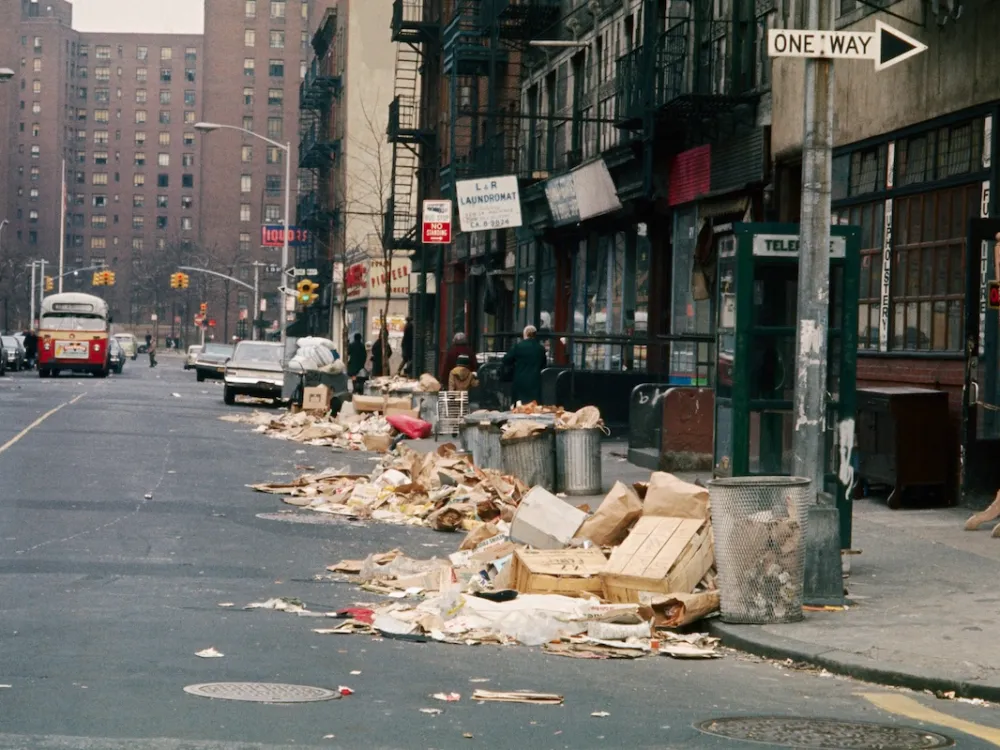 Excess garbage from trash cans spills into the street at curb at Avenue B and 12th Street as New York City garbage collectors
