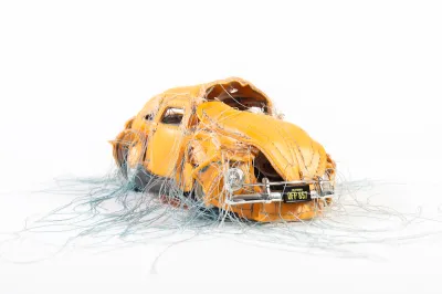 A vinyl sculpture depicting a car strung with thread that pours of its windows and other parts.