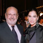 A photo shows a man and a woman, Maurice Alain Amon and then-wife Tracey Amon, at an event in Paris. he wears a dark suit, she a dark jacket and large dark earrings