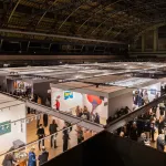 Aerial view of an art fair gallery with people in the aisles.
