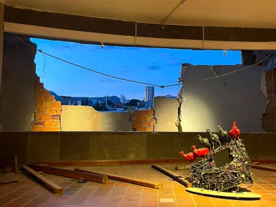 A collapsed wall shows the sky outside of a museum. 