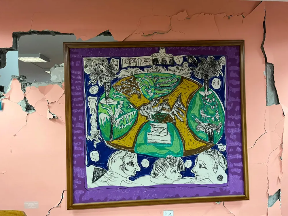 A painting showing figures looking at a plaza hangs from a crumbling pink wall.