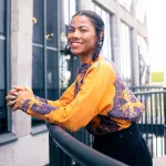Portrait of Zohra Opoku leaning over a balcony.