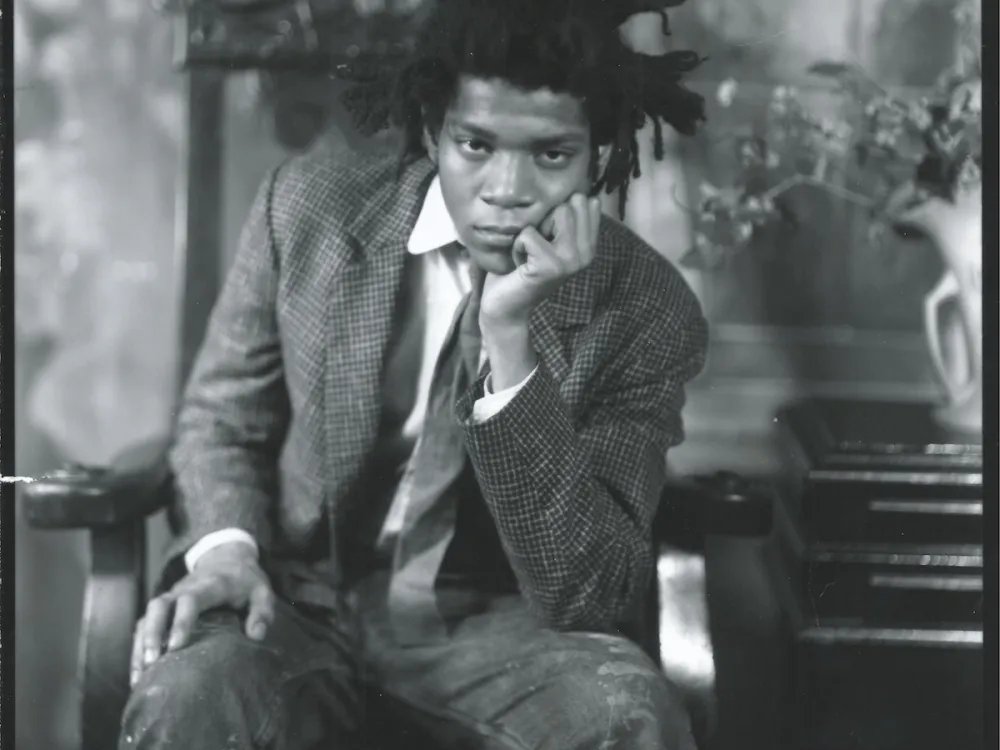 Black-and-white portrait of Jean-Michel Basquiat, seated with his hand supporting his head, in 1982.