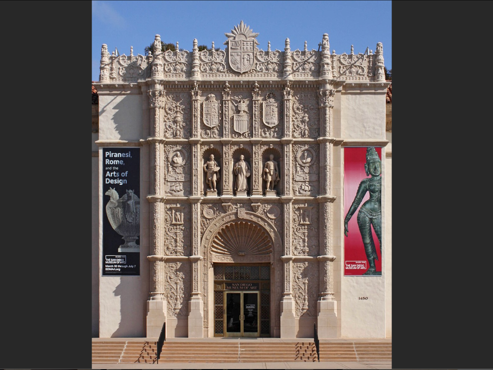 ornate facade of a museum building with an arched entryway and banners on either side