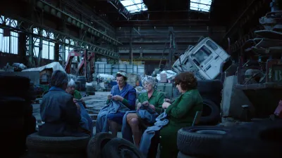 A video still of women knitting in a car factory.