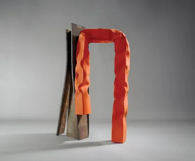 A sculpture of found iron next to an orange-painted metal that is bent and warped.