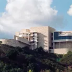 A curvilinear white and beige building on a hillside.