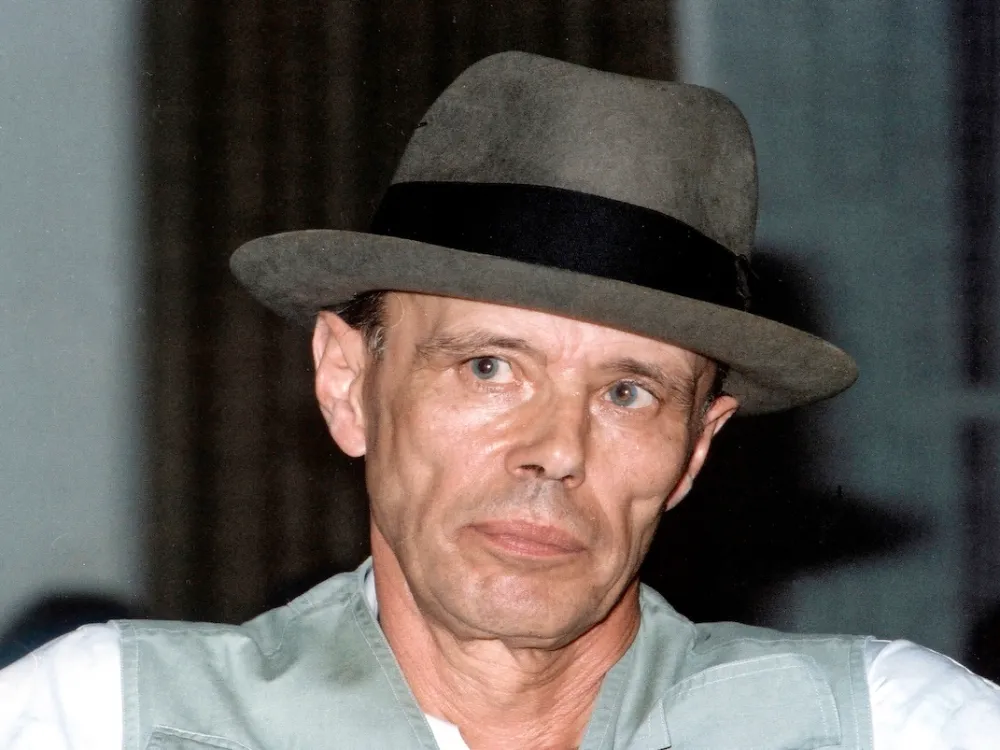 Portrait of Joseph Beuys wearing a bowler hat and a green vest.