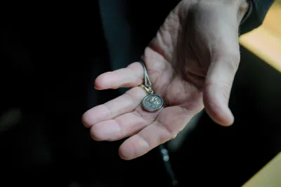 A hand holding a coin on a necklace.