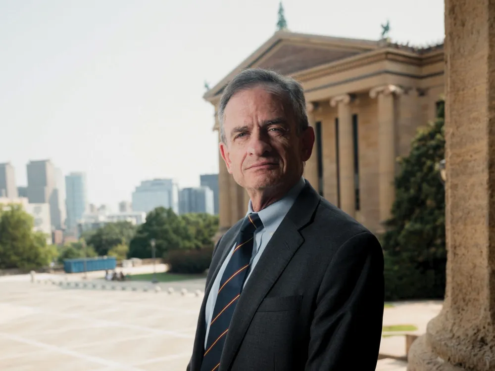 A man in front of a columnated museum.