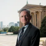 A man in front of a columnated museum.