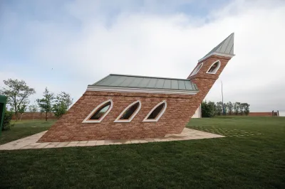 A sculpture of a church and a steeple that appears to blow in the wind into an angle.
