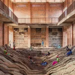 People lying on a ridged floor in a red-bricked building.