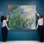 Two art handlers install Claude Monet’s large-scale painting Iris (1924–25), depicting flowers and foliage in his garden at Giverny, at Sotheby’s Paris.