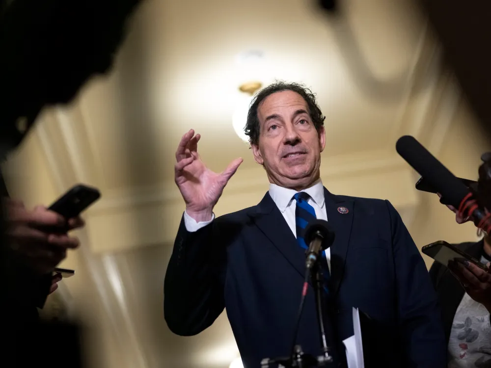 Rep. Jamie Raskin (D-MD) speaks to reporters, wearing a business suit, surrounded by microphones, gesturing with his hand as he speaks.