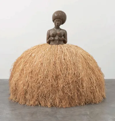 A sculpture of a bare-breast woman with a raffia skirt.
