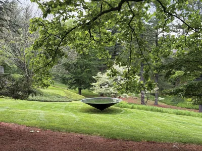 An inverted cone sculpture in a wooded area.