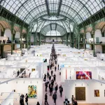 People walking among booths in a domed building.