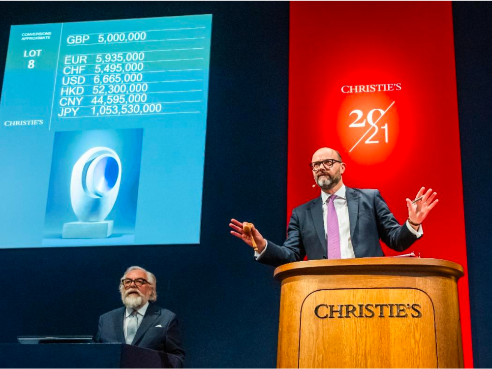Auctioneer Nicholas Orchard takes bids at Christie’s London as Barbara Hepworth’s Sculpture with Colour (Eos) (1946) appears on a large screen behind him.