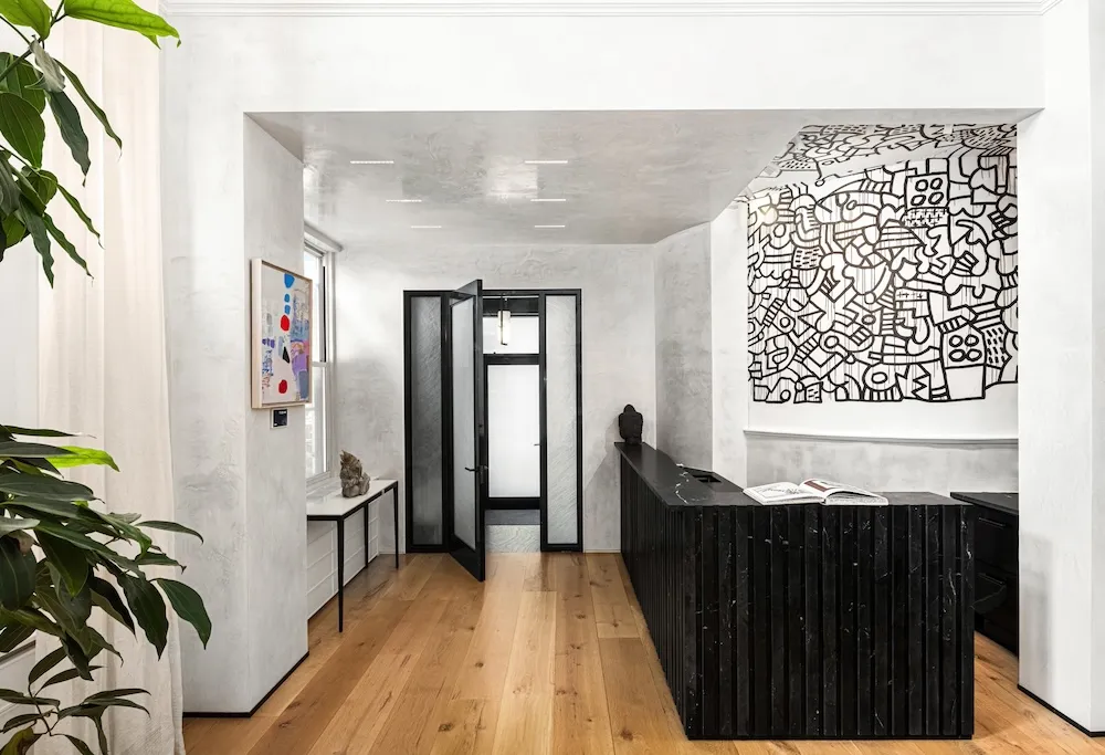 Black-and-white Keith Haring mural covering a wall and part of the ceiling above a black bar in a modern Tribeca apartment with white walls and wood floors.