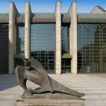 Exterior of a stone and glass museum building with a bronze sculpture in front